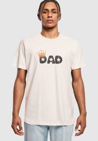 Lyserød bomulls t-skjorte med svart "DAD" tekst og et gullkrone-design over, med to svarte stjerneakenter på hver side.