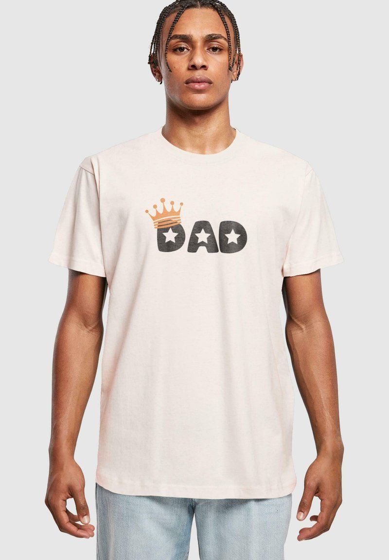 Lyserød bomulls t-skjorte med svart "DAD" tekst og et gullkrone-design over, med to svarte stjerneakenter på hver side.