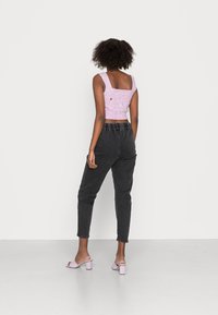 Pink knitted crop top with square neckline, paired with black high-waisted pants featuring an elastic waistband, and light purple block-heeled sandals.