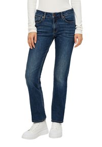 Tumed sinised denim teksad sirge jala disainiga, kontrastsete õmblustega ja ees olevate taskutega, koos valgete platvormkingadega.