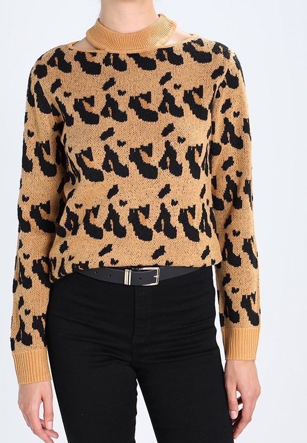 Tijgerprint trui in bruin en zwart, gemaakt van gebreide stof. Heeft een geribbelde halslijn en lange mouwen, gecombineerd met zwarte broeken.