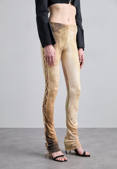 Leggings bej cu talie înaltă, cu un finisaj texturat, având un detaliu cu șiret pe lateral și un gradient de la tonuri închise la tonuri deschise.