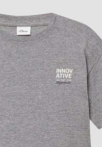 Grijze katoenen t-shirt met een ronde hals. Bevat gedrukt wit tekst "INNOVATIEVE JONGE STUDIO ACADEMIE AFDELING" op de borst.