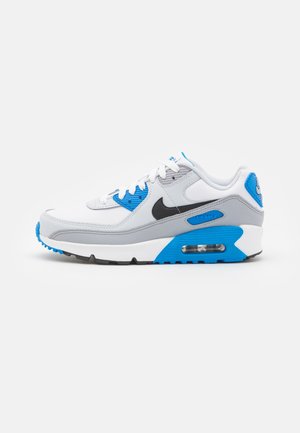 Hvide, grå og blå Nike Air Max sneakers med sort swoosh, synlig luftdæmpningssål og hvide snørebånd på en hvid baggrund.