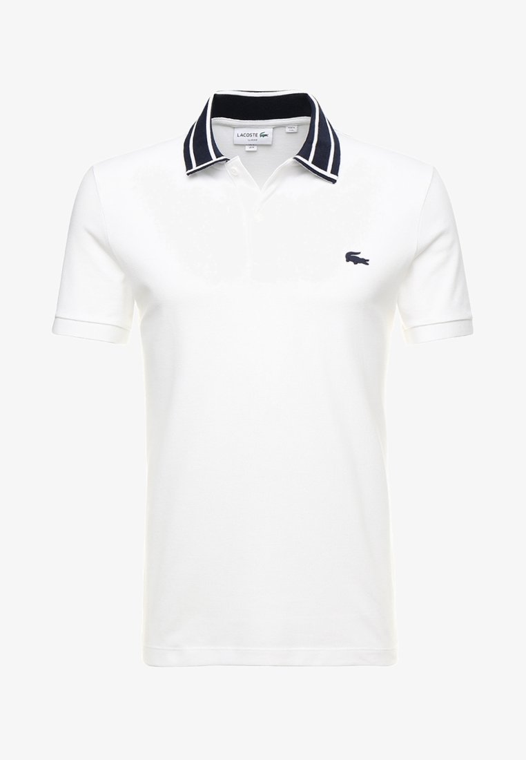 White polo shirt made of cotton, featuring a navy striped collar and a small navy crocodile logo on the chest. Short sleeves, classic design.