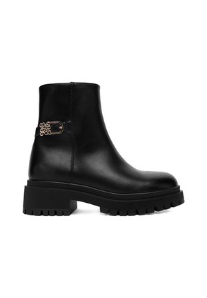 Bota de cuero negra hasta el tobillo con suela gruesa de tacos y tacón bajo de bloque, con una hebilla dorada decorativa en el lado.