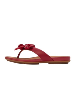 Red leather flat sandal with toe thong and flower embellishments on a tan sole.