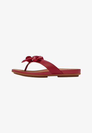 Red leather flat sandal with toe thong and flower embellishments on a tan sole.