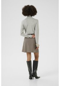 Šedý rolák, hnědá kostkovaná sukně a černé vysoké stiletto boty; hladká textura, přiléhavý střih a neutrální odstíny.