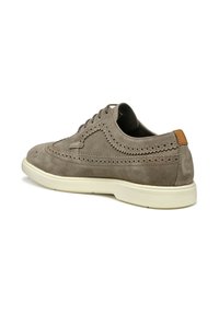 Chaussure en suède gris à lacets avec des détails perforés, bout rond et semelle en caoutchouc crème. Présente un onglet de talon en cuir tan.