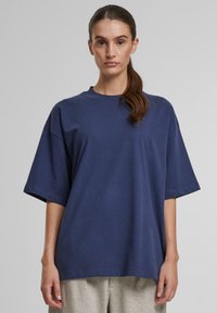 Marineblå oversized t-shirt lavet af bomuld med rund hals og korte, brede ærmer. Stoffet ser glat ud med en afslappet pasform.