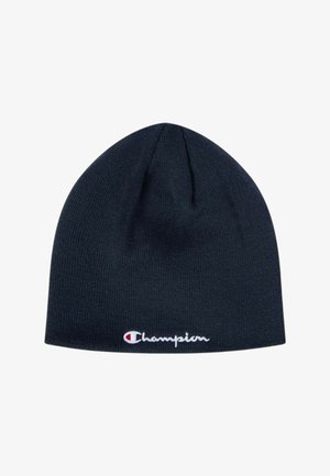 Berretto a maglia blu navy scuro con logo Champion bianco e rosso ricamato vicino al bordo inferiore su uno sfondo bianco semplice.