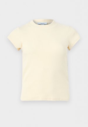 Krémový žebrovaný top s krátkými rukávy a kulatým výstřihem, vyrobený z elastické tkaniny, zobrazený na jednobarevném světle šedém pozadí.