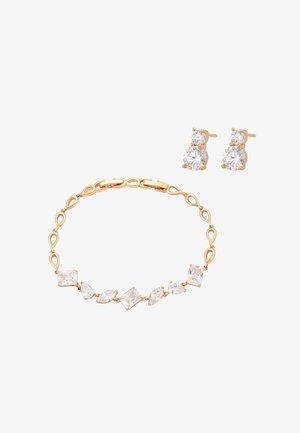 Złota bransoletka z różnorodnymi, przezroczystymi kamieniami szlachetnymi oraz pasujące złote kolczyki wkrętki z dwoma okrągłymi, przezroczystymi kamieniami.