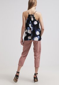 Svart blommig linne med flerfärgade blommor, ihopparat med rosa capribyxor och svarta högklackade skor, med tunna axelband och en slits bak.