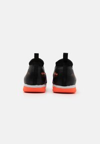 Sorte atletiske sko med orange accenter og en struktureret finish. Har trækflapper bagpå og grå såler. Simpelt, strømlinet design.