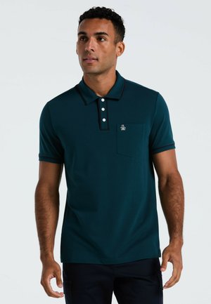 Teal poloshirt van zacht stof met marineblauwe trim, drieknopen sluiting, zak op de linkerborst en een klein logo-detail.