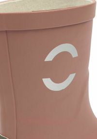 Rosa gummistövel med en texturerad yta och ett stort vitt cirkelformat mönster. Insidan är fodrad med ett ljust tyg.