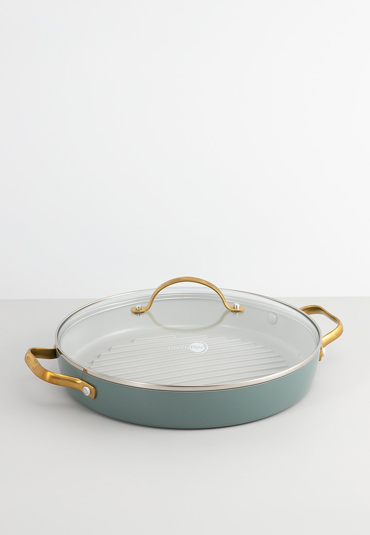 Poêle bleu-vert avec un couvercle en verre, des poignées dorées et une surface de cuisson striée, dotée d'un bord en acier inoxydable et d'un logo.
