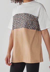 Farvet blokke t-shirt med hvid top, leopardprint i midten og beige bund. Lavet af bomuld, med en afslappet pasform og korte ærmer.