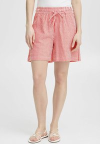 Pantaloni corti a righe rosse e bianche con vita elastica e cordoncino. Presentano tasche laterali e una vestibilità rilassata. Tessuto di cotone morbido.