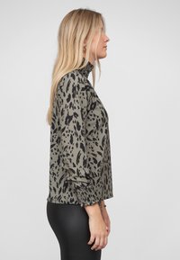 Langærmet skjorte i olivengrøn med sort dyreprint, med høj krave og indsamlede manchetter. Glat stof med en afslappet pasform.