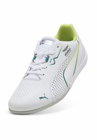 Weißer Turnschuh mit durchbrochener Oberseite, grünen Akzenten und gepolsterter Ferse. Verfügt über eine strukturierte Sohle und das PUMA-Logo an der Seite.