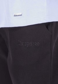 Lyseblå T-shirt med en sølvmærke over sorte ribbede bukser med tonal "Dropside" broderi på benet.
