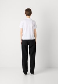 White cotton t-shirt, short sleeves, crew neck, paired with loose-fitting black pants. Simple design, minimal detailing, no visible patterns.