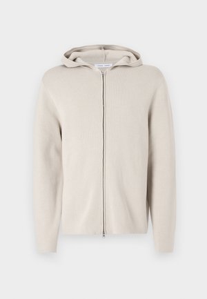 Felpa zip beige con una texture morbida, dotata di cappuccio, maniche lunghe e una linea dritta. Design minimalista senza decorazioni.