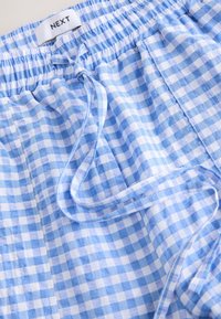 Modri in beli kratasti kratki hlače z elastičnim pasom, z vrvico in mehko teksturo tkanine. Oznaka blagovne znamke na pasu.