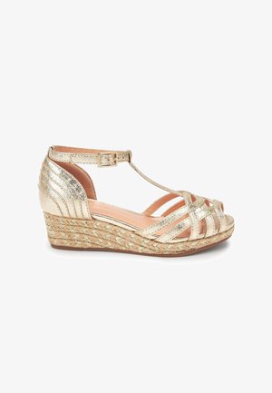 Sandal in oro con design a strisce incrociate, suola in juta intrecciata e finitura metallica. Chiusura con fibbia alla caviglia; punta e tallone aperti.