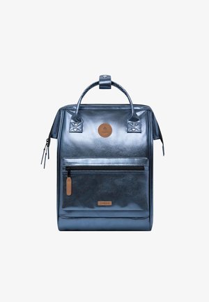 Metallisch blauer rechteckiger Rucksack mit Tragegriffen oben, vorderer Reißverschlusstasche und braunen Markenaufnähern auf weißem Hintergrund.