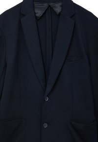 Dunkelblazer in Marineblau mit zwei Knöpfen, Revers und drei Fronttaschen, kombiniert mit einem passenden dunklen Hemd darunter.