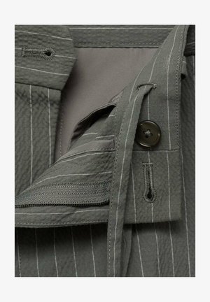 Sivkasta tkanina z navpičnimi belimi črtami, ki ima gumbasto zapiranje in žep z zadrgo. Gladka tekstura s plastevnimi oblikovalskimi elementi.