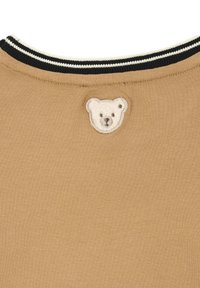 Beige T-Shirt-Stoff mit weicher Textur, ausgestattet mit einem schwarz-weißen gestreiften Kragen und einem gestickten Bärenmotif auf dem Rücken.