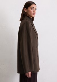 Braun melierter, oversized Blazer mit Reverskragen, doppelreihigem Design und zwei Fronttaschen. Glatte Textur und schlichte Knöpfe.