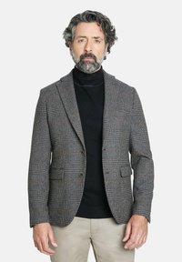 Blazer de cuadros gris para hombre, fabricado en tejido texturizado, con cierre de dos botones, solapas con muesca y bolsillos frontales, llevado sobre un cuello de tortuga negro.