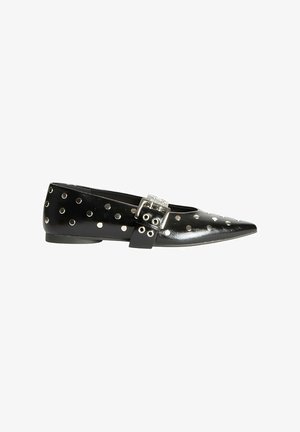 Zapato plano de charol negro con punta afilada, decorado con tachas plateadas y un hebilla en la correa del tobillo. Textura suave, diseño minimalista.