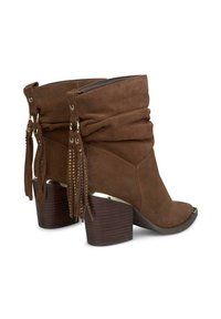 Botas de tobillo de ante marrón con un diseño arrugado, acentos de flecos y un tacón grueso de madera. Estilo destalonado con un borde metálico en la parte del pie.