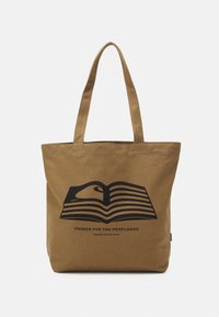 Ruskeasta kankaasta valmistettu olkalaukku, jossa on kaksi hihnaa. Laukussa on musta kuvio avoimesta kirjasta, raidat ja teksti "PRIMER FOR THE PERPLEXED."