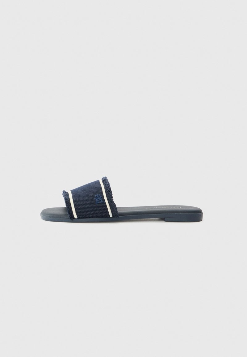 Sandale slide bleu marine avec une large bride en tissu comportant des rayures blanches et un détail brodé subtil, semelle plate et bout ouvert.