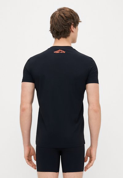 Maglietta sportiva nera con colletto rotondo, maniche corte e un piccolo logo arancione sulla nuca. Texture liscia e design aderente.