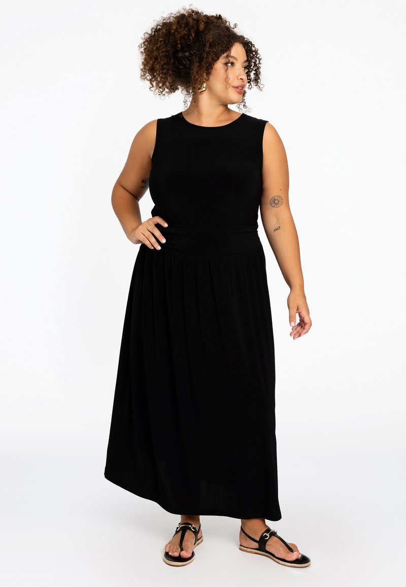 Zwarte mouwloze maxi jurk met een getailleerde taille en een vloeiende rok. Gemaakt van zachte stof, met een ronde halslijn en minimale details.