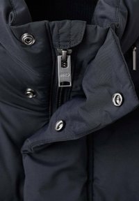 Chaqueta acolchada de color marino con cierre de cremallera y herrajes plateados, botones a presión y tejido texturizado para aislamiento y calidez.