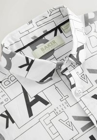 Balta pogā piegriezta krekla ar ģeometrisku melnu un pelēku burtiem. Satur apkakles izmēru un zīmola etiķeti iekšpusē apkaklē.