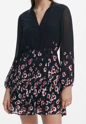 Black long-sleeve dress with red and white floral pattern, V-neck, buttoned front, cinched waist with thin belt, and pleated skirt.