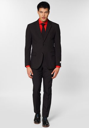 Schwarzer Anzug mit einreihigem Sakko, rohem Hemd und passender Krawatte. Enthält schwarze Dressschuhe mit blauen Schnürsenkeln und taillierte Passform.