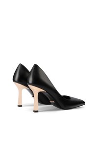 Scarpe con tacco alto in pelle nera con punta affilata, dotate di un dettaglio intagliato e un tacco stiletto beige con base nera.