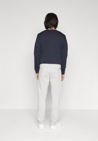 Un sweatshirt bleumarin cu guler rotund, asortat cu pantaloni gri deschis. Întreaga ținută are un design simplu și este realizată dintr-un material din bumbac, cu detalii minime.
